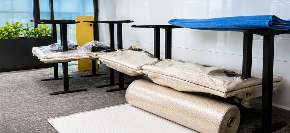 Baloncuklu naylon ve yorgan battaniyeyle sarılıp streçlenmiş masa tablaları ile rulo balonlu naylon — nakliyatta eşyaların paketlenmesi